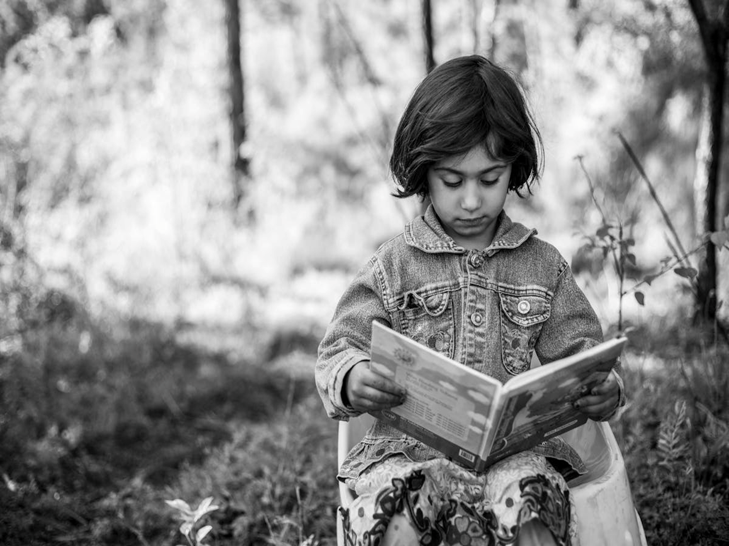 A young girl reading a book outdoors